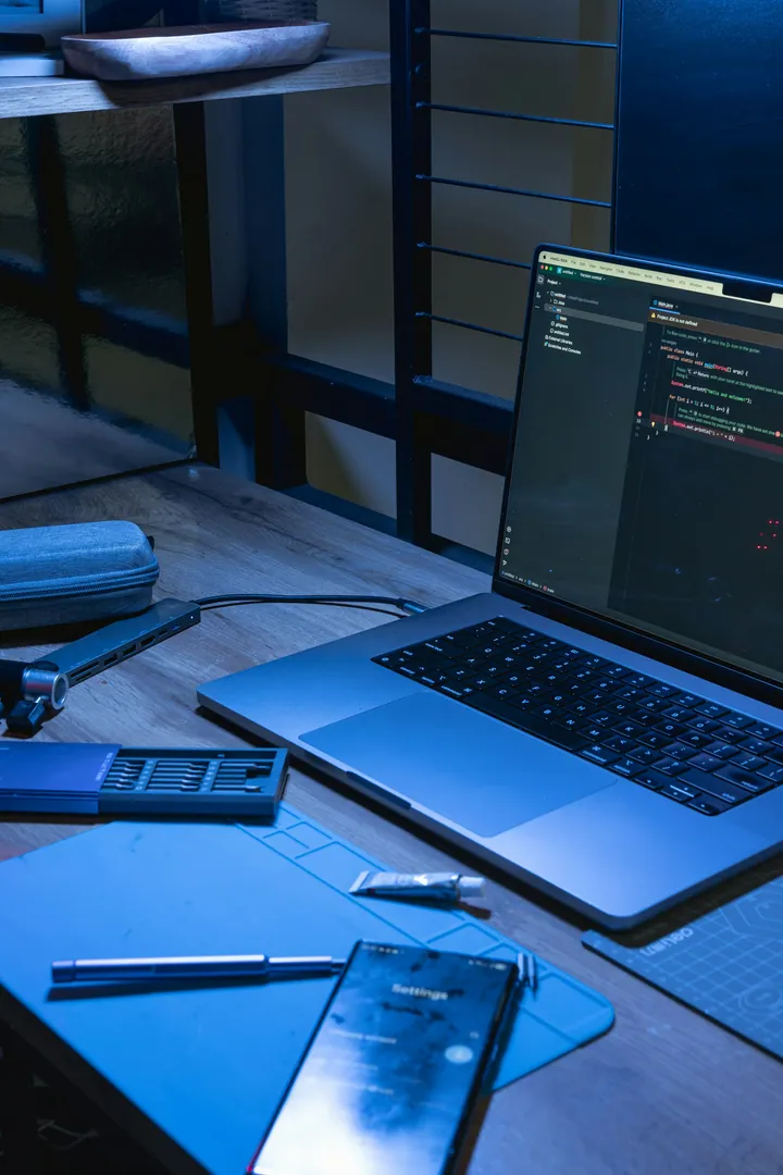 Ordinateur portable affichant du code sur un bureau en bois.